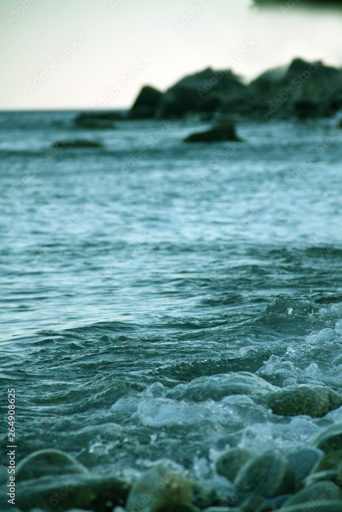 Fototapeta premium Shores of the Aegean sea. Stone beach. The wave rolls on the shore. Travel and tourism business.