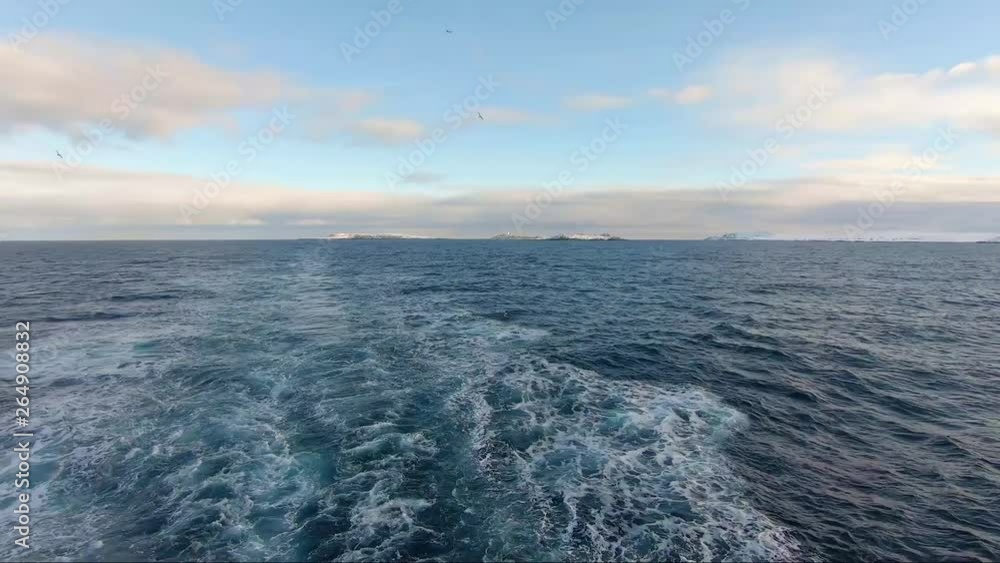 Ship moving through arctic water POV rear of ship with birds flying Ship moving through arctic water POV rear of ship with birds flying