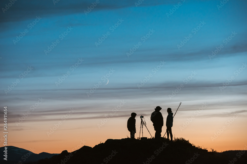 Silhouettes of photographers against sunset sky