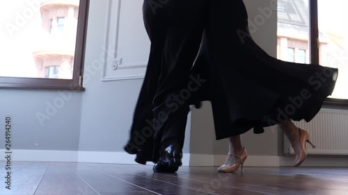 Ballroom dancers couple pare performing dancing on parquet floor with natural light from the window