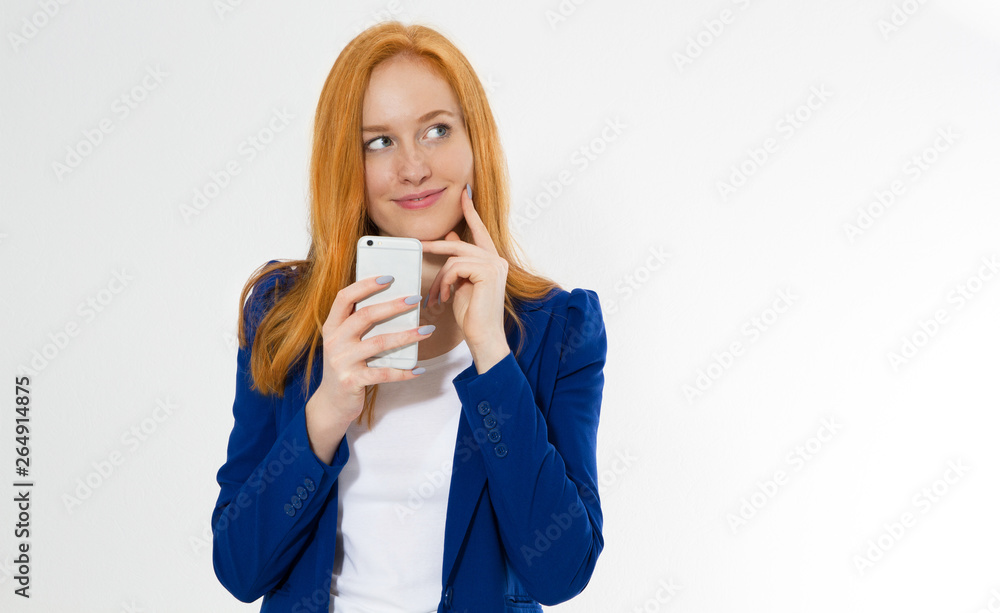 Pretty redhead girl with phone smiling isolated on white background. Young foxy female in business outfit, has amazed look, indicates with fore finger at right upper corner, shows. Pretty redhead girl with phone smiling isolated on white background. Young foxy female in business outfit, has amazed look, indicates with fore finger at right upper corner, shows.