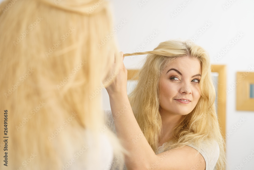 Fototapeta premium Woman in bathroom styling hair