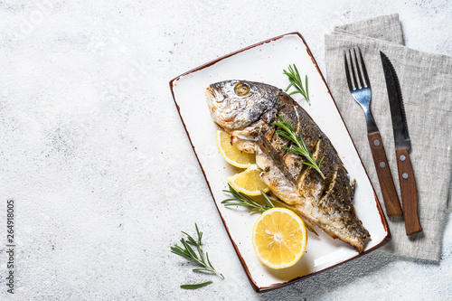 Baked dorado fish with lemon and rosemary top view.