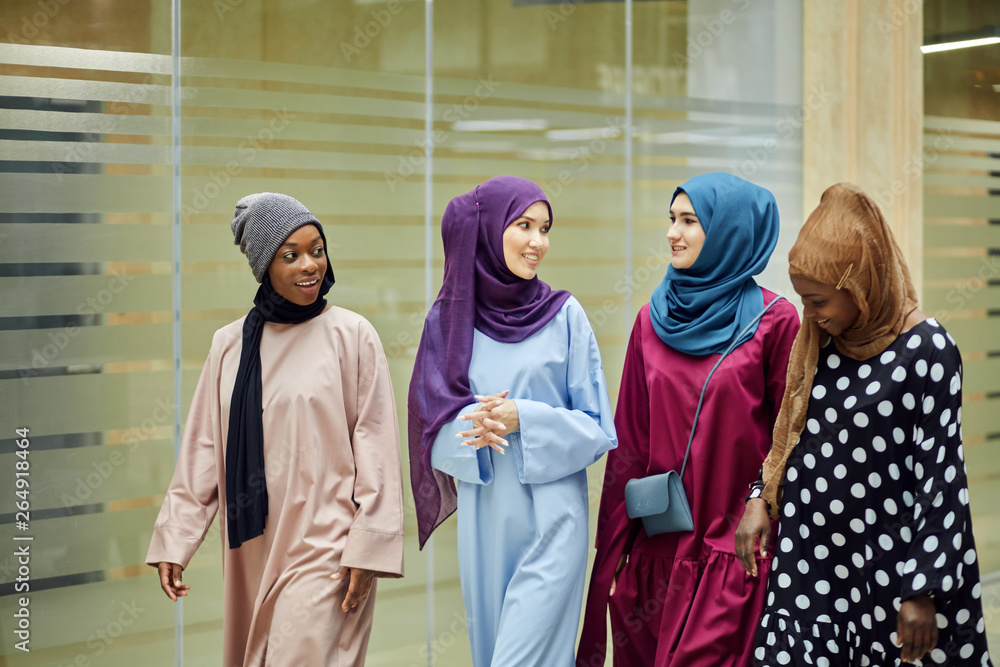 A group of four young islamic multiethnic girls chatting and walking together outdoor