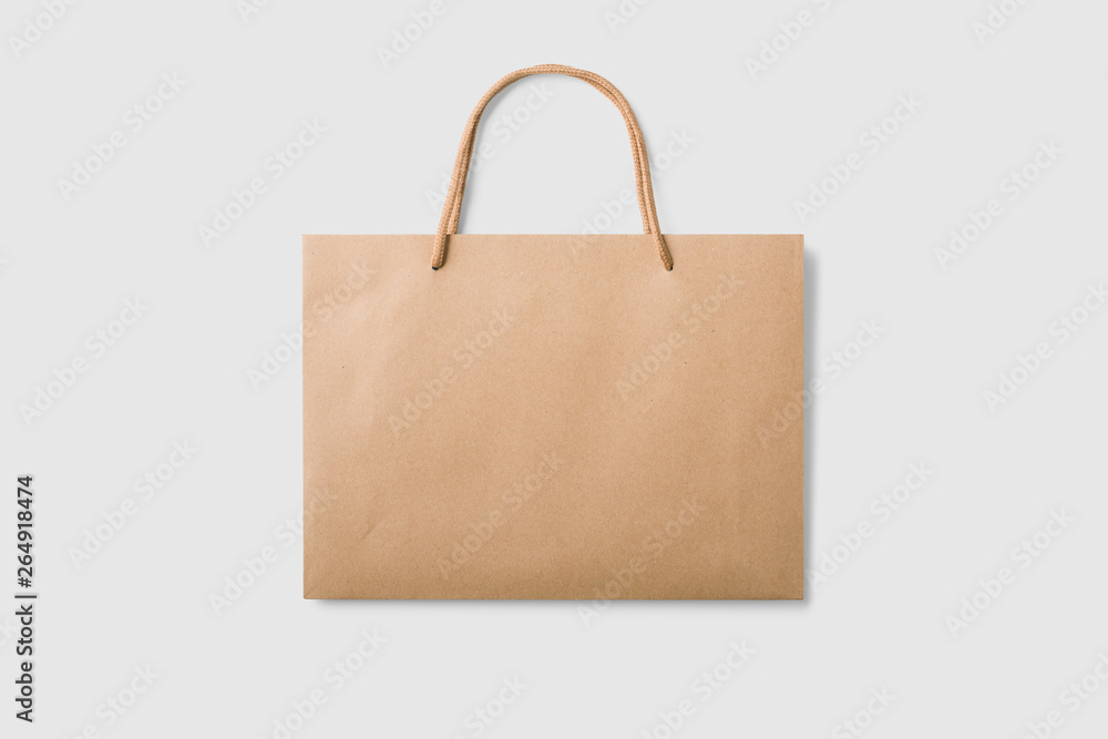 Mockup of a blank kraft paper shopping bag with handles on light grey background. High resolution.