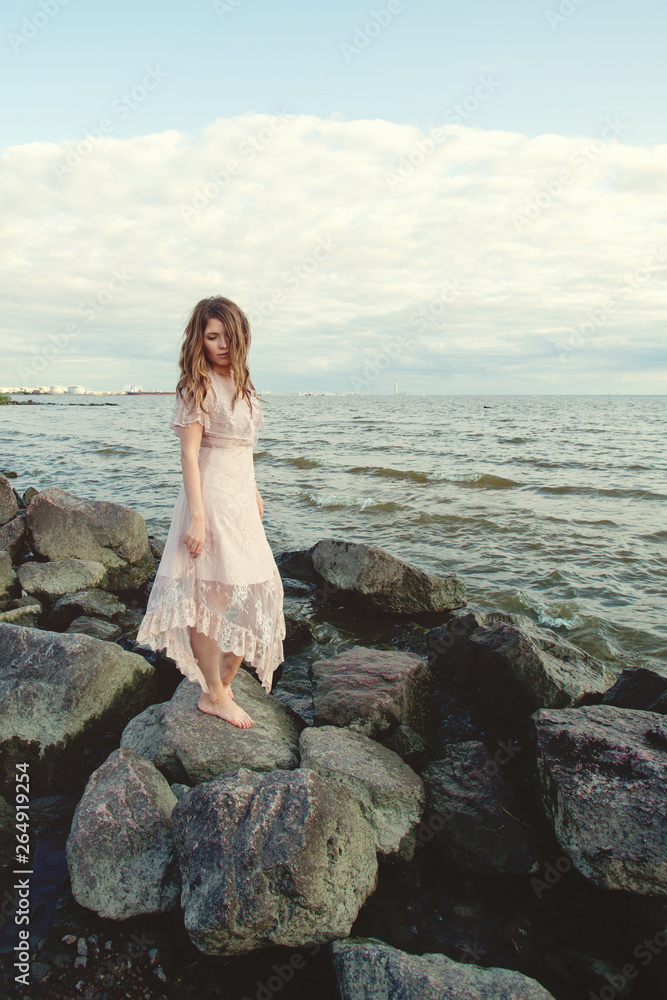 Beautiful woman wearing boho dress on ocean coast, romantic beauty portrait Beautiful woman wearing boho dress on ocean coast, romantic beauty portrait