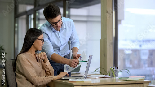 Photography Two company employees preparing report, comparing graphics, business career