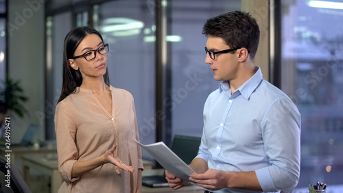 Slika na platnu Strict business woman checking work of male trainee, demanding company boss