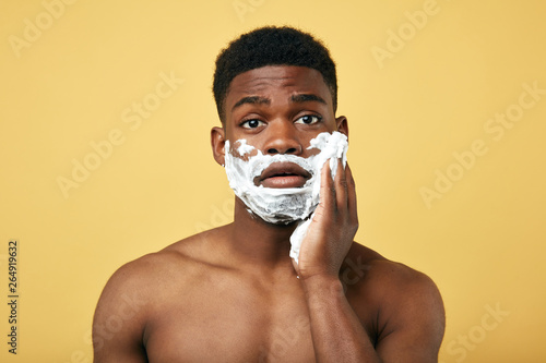 grooming concept. Puzzled African man going to shave beard, poses half naked,daily routine. pastime photo