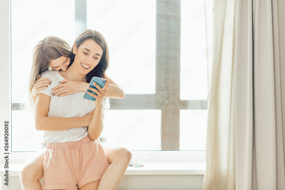 cheerful positive girls having great time, joking while using a gadget. ha-ha,girls remember funny moments from their childhood. copy space. carefree life cheerful positive girls having great time, joking while using a gadget. ha-ha,girls remember funny moments from their childhood. copy space. carefree life