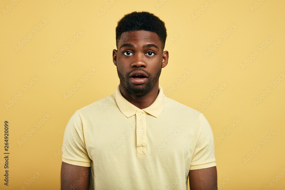 Bearded stylish awesome male having displeased look standing against yellow background., being puzzled, doesn't know what to say,emotion, feeling Bearded stylish awesome male having displeased look standing against yellow background., being puzzled, doesn't know what to say,emotion, feeling