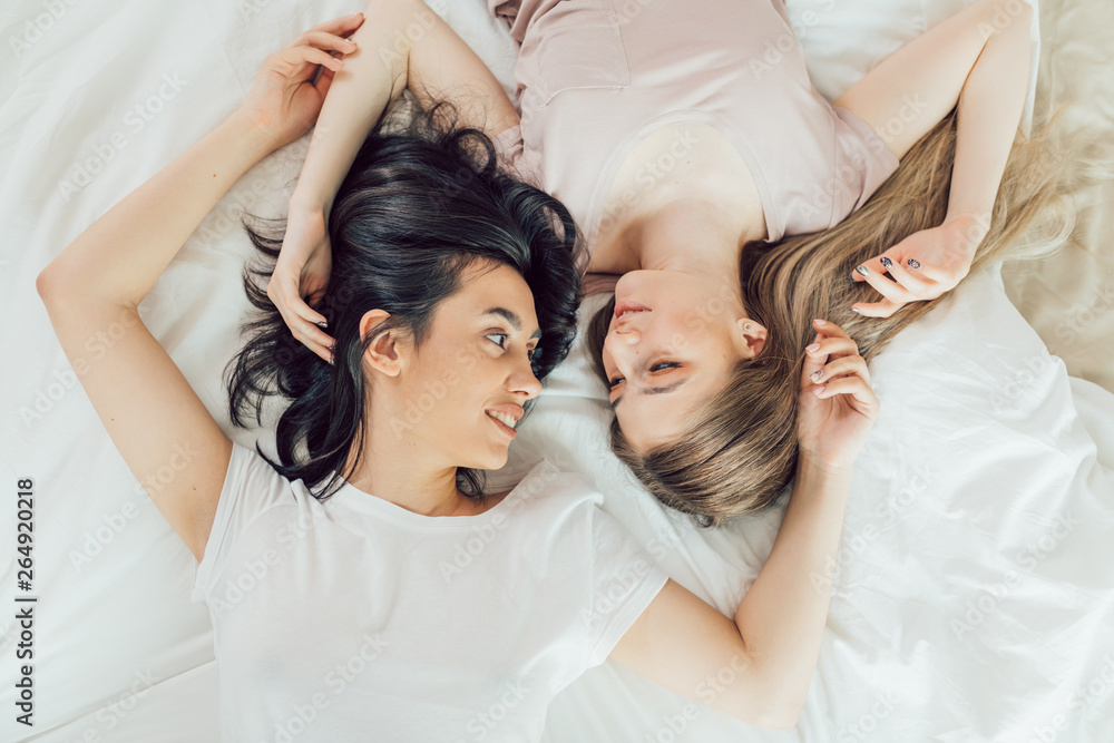 Φωτογραφία women with fair and dark hair spinding time on the bed,lifestyle, pastime with l