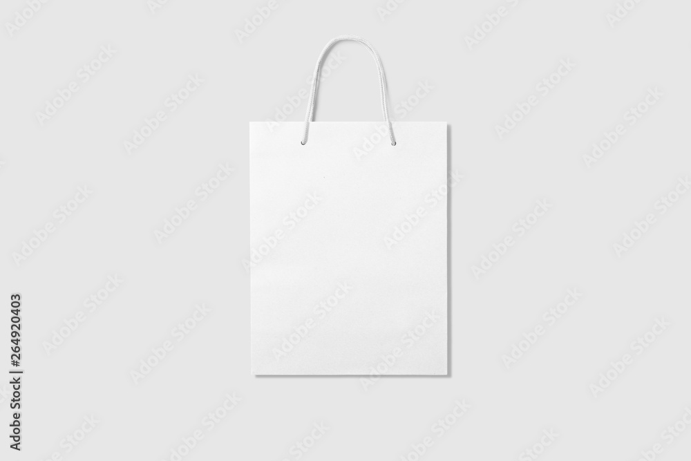 Mockup of a blank white paper shopping bag with handles on light grey ...