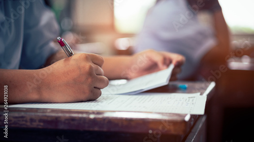 Hand of students taking exam with stress in classroom