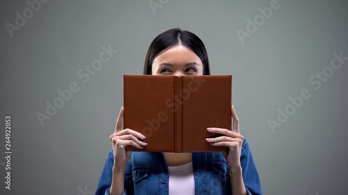 Woman making plans and thinking over business strategy hiding behind notebook © motortion
