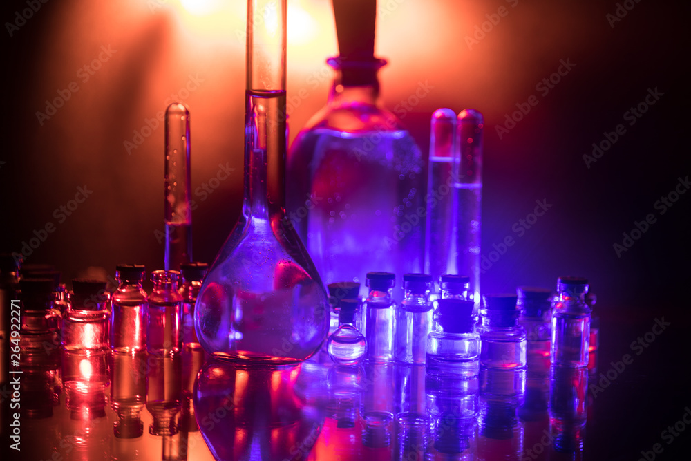 Pharmacy and chemistry theme. Test glass flask with solution in research laboratory. Science and medical background. Laboratory test tubes on dark toned background Pharmacy and chemistry theme. Test glass flask with solution in research laboratory. Science and medical background. Laboratory test tubes on dark toned background
