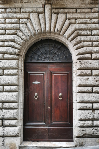 Ancient wooden portal with carved stone arch of an Italian medieval fortress.