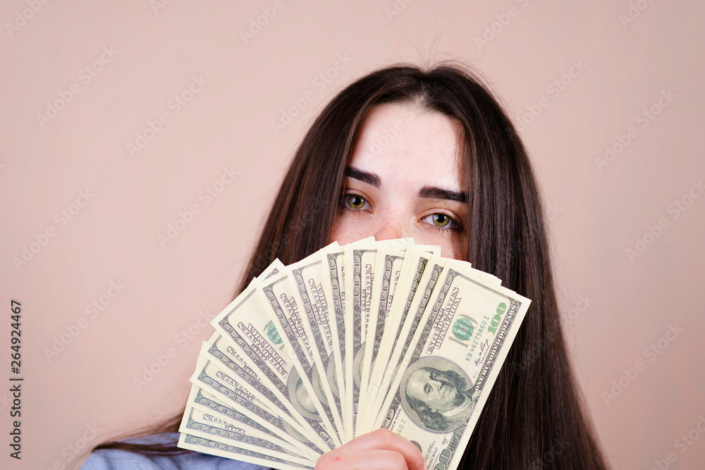 Beautiful young woman joyfully holding in her hand a lot of dollars. savings, earning, money and banking, purchases and shopping Beautiful young woman joyfully holding in her hand a lot of dollars. savings, earning, money and banking, purchases and shopping