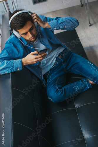 young man in the apartment with phone and headphones © carballo