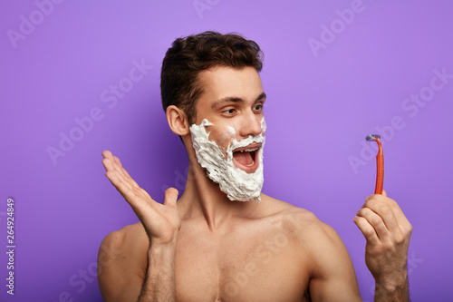 funny emotional guy talking with a shaver. madness concept.guy using a disposable razor for the first time photo