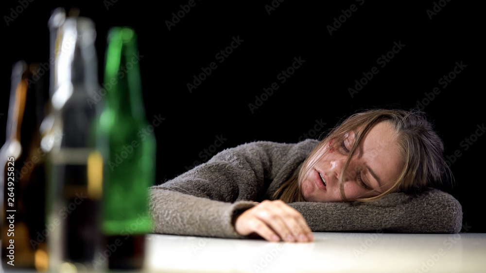 Obraz premium Addicted female sleeping on table after drinking alcohol, harmful health effect