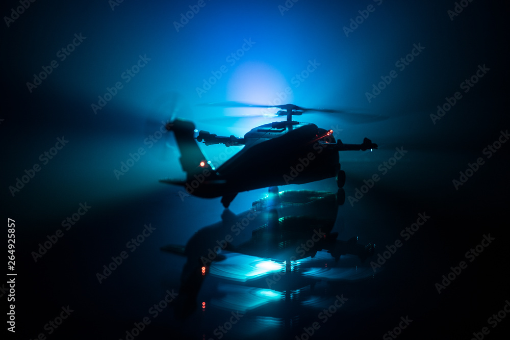 Silhouette of military helicopter ready to fly from conflict zone. Decorated night footage with helicopter starting in desert with foggy toned backlit. Selective focus.