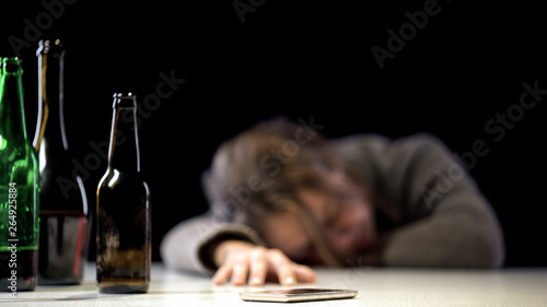 Foto Female suffering alcohol poisoning sleeping near phone on table, medical care