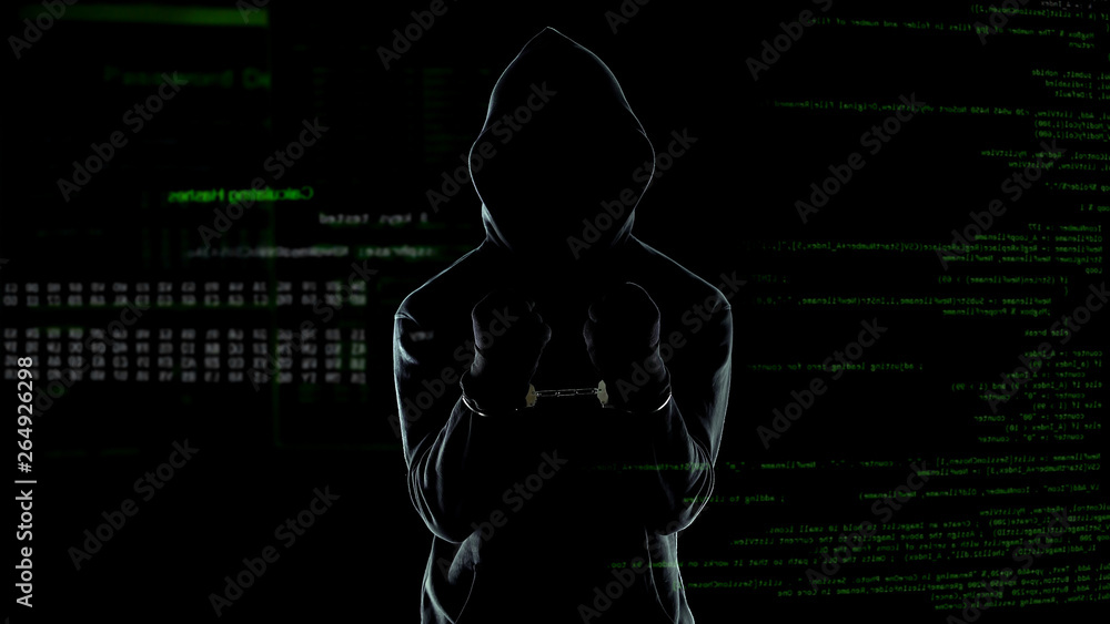 Silhouette of handcuffed angry hacker on animated computer code ...