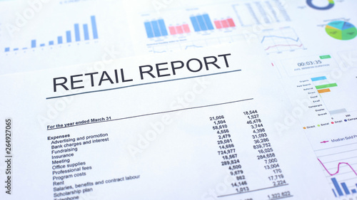 Retail report lying on table, graphs charts and diagrams, official document