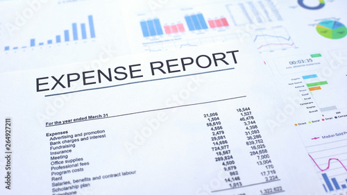 Expense report lying on table, graphs charts and diagrams, official document