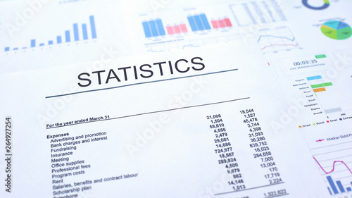 Statistics official document lying on table, graphs charts and diagrams, text