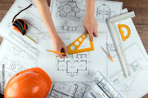 Male hands, Orange helmet, pencil, architectural construction drawings, tape measure. The architect designs the building. The concept of architecture, construction, engineering, design. Copy space.