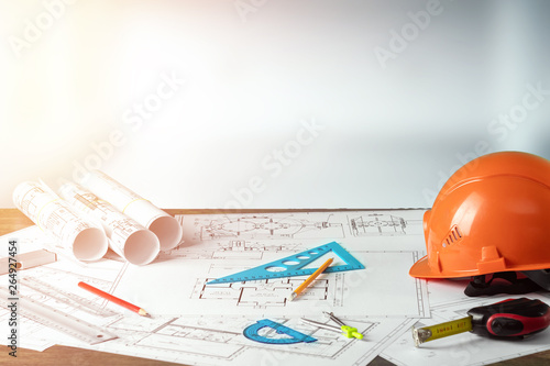 Orange helmet, pencil, architectural construction drawings, tape measure. The concept of architecture, construction, engineering, design. Copy space.