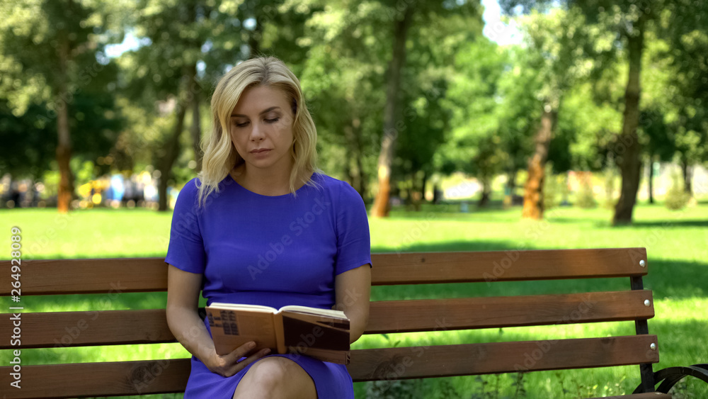 Beautiful lady reading book in park, sitting on bench, spending free time, hobby Beautiful lady reading book in park, sitting on bench, spending free time, hobby