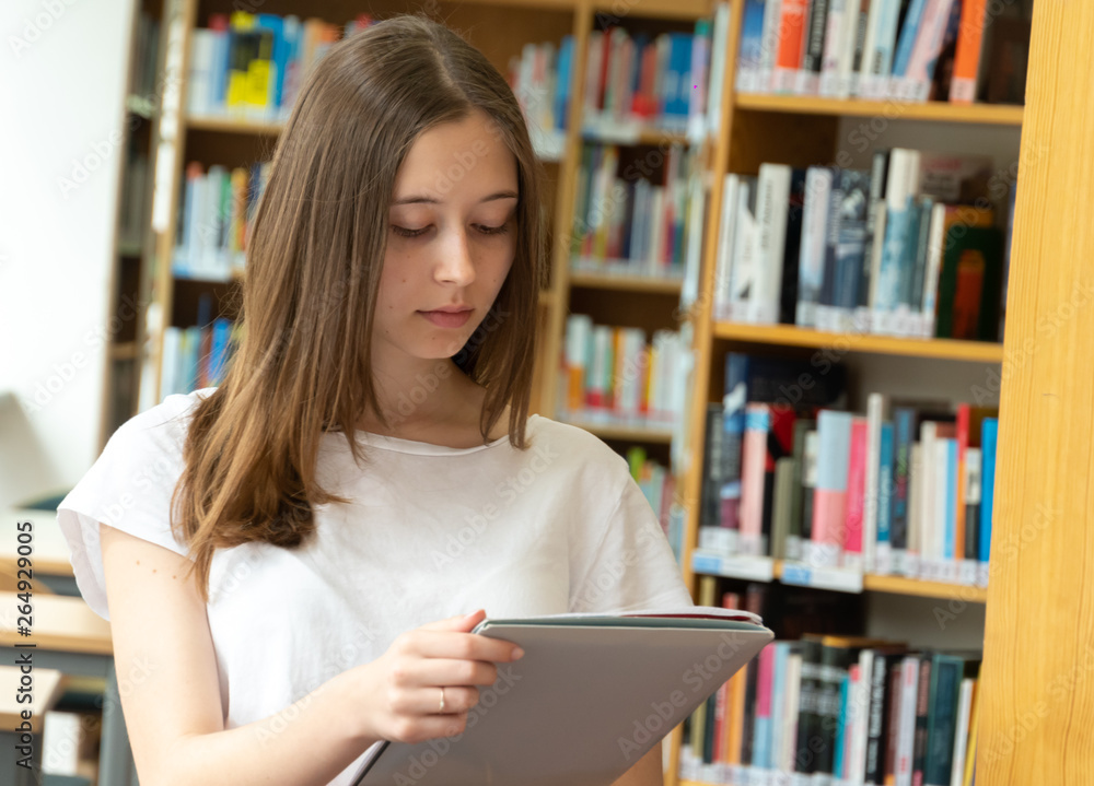 Portrait of a concentrated girl standing reading in the school library Portrait of a concentrated girl standing reading in the school library