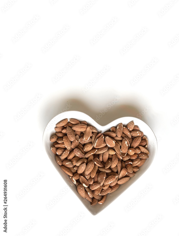 Nuts arranged in heart on background. Healthy Food image close up almond on the cup plate. Love Texture on white grey table top view mock up Nuts arranged in heart on background. Healthy Food image close up almond on the cup plate. Love Texture on white grey table top view mock up