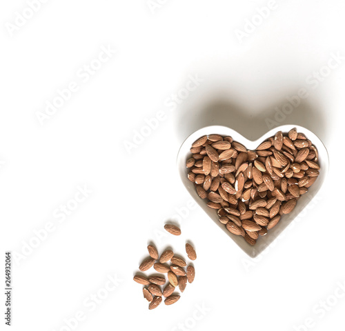 Nuts arranged in heart  on background. Healthy Food image close up almond on the cup plate. Love Texture on white grey table top view mock up © Evgenia
