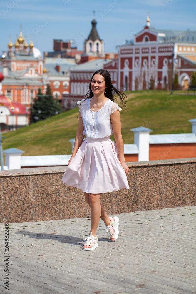 Young brunette woman in pink skirt and white blouse