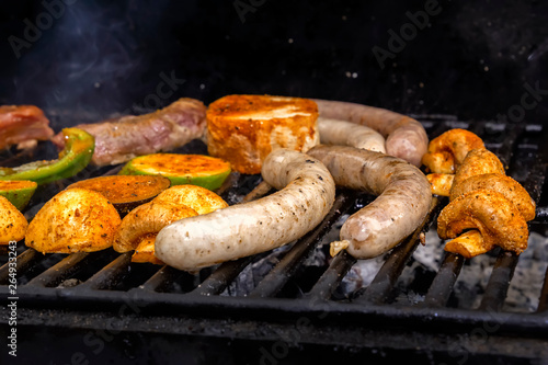 Sausages, meat steak, vegetables, mushrooms are cooked on a charcoal grill. Street food. Close-up