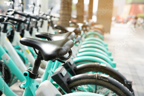 Bicycle rental service on city road parking with sunlight, public transportation concept.