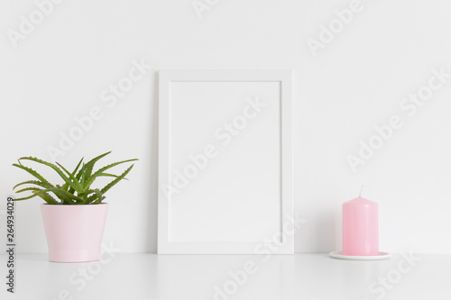 White frame mockup with a succulent plant and a candle on a white table. Portrait orientation.
