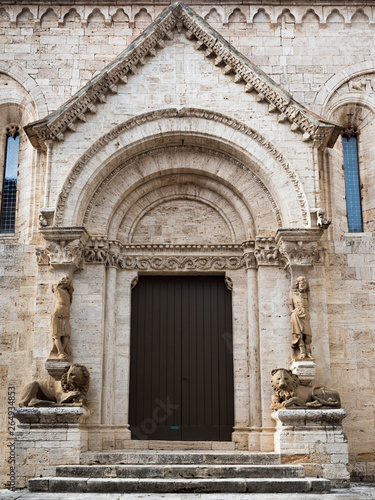 The carved stone entrance with columns of statues and stone lions of the abbey of San Quirico d'Orcia, Italy,