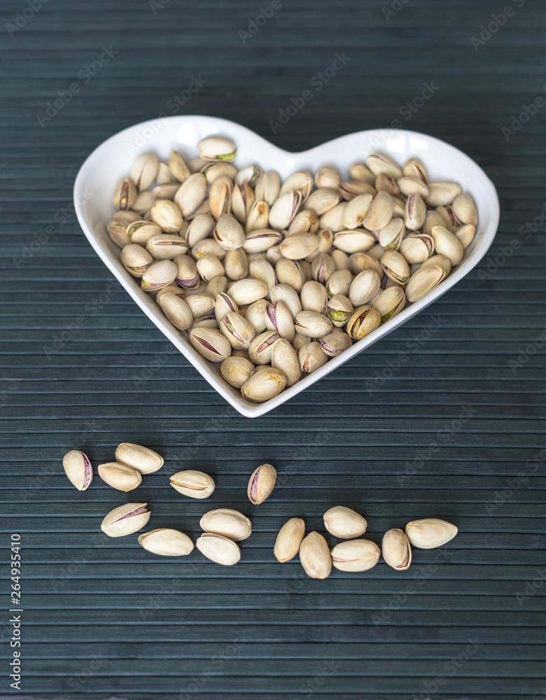 Nuts arranged in heart on background. Healthy Food image close up pistachios on the cup plate. Love Texture on top view mock up Nuts arranged in heart on background. Healthy Food image close up pistachios on the cup plate. Love Texture on top view mock up