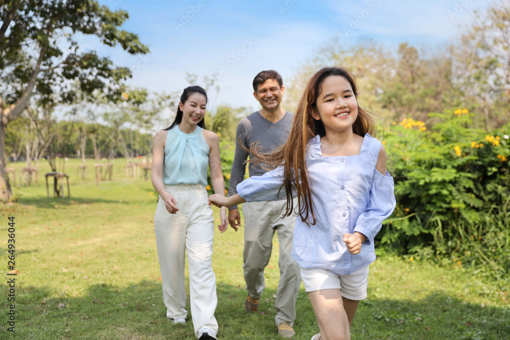 happy asian family parents and children are resting by walking and running in the park during summer season with clear blue sky and green trees happy asian family parents and children are resting by walking and running in the park during summer season with clear blue sky and green trees