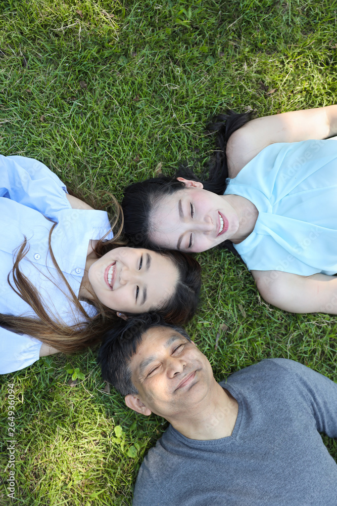 top view of lovely and joyful family looking at camera and smiling while lying on the grass filed during summer time top view of lovely and joyful family looking at camera and smiling while lying on the grass filed during summer time