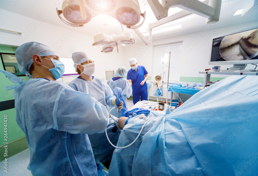 Arthroscope surgery. Orthopedic surgeons in teamwork in the operating room with modern arthroscopic tools. Knee surgery. Arthroscope surgery. Orthopedic surgeons in teamwork in the operating room with modern arthroscopic tools. Knee surgery.