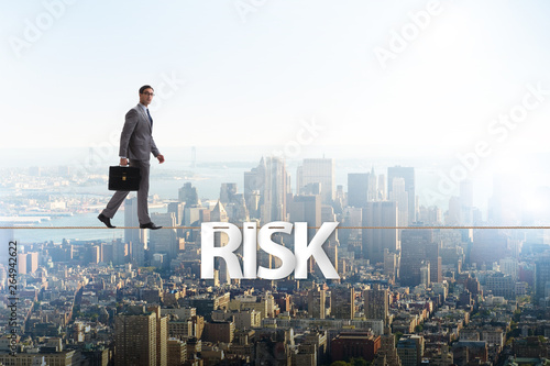 Businessman in risk concept walking on tight rope photo