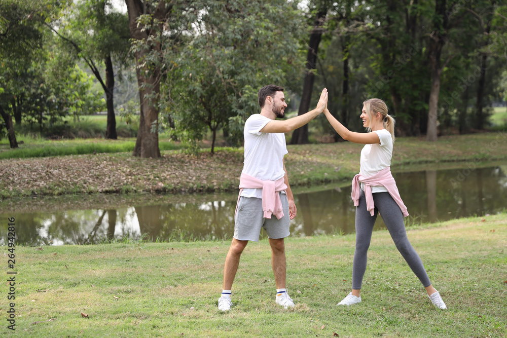young and healthy couple people enjoying in exercising outdoor and they posting give me five with green trees during summer time in the park young and healthy couple people enjoying in exercising outdoor and they posting give me five with green trees during summer time in the park