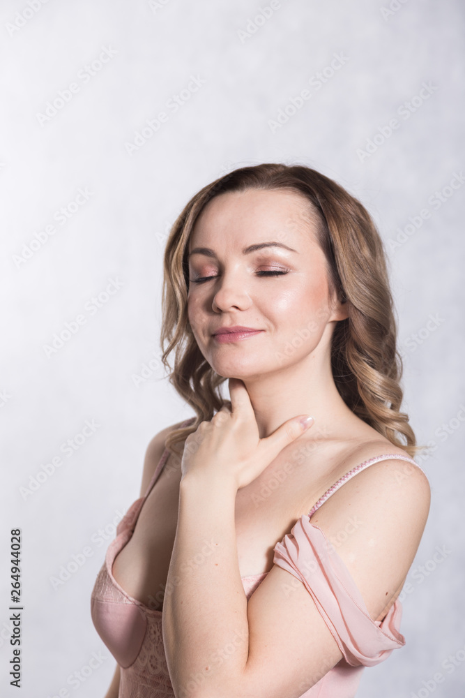 Portrait of beautiful young elegant female in pale pink wedding dress with big neckline, on a white background. Portrait of beautiful young elegant female in pale pink wedding dress with big neckline, on a white background.