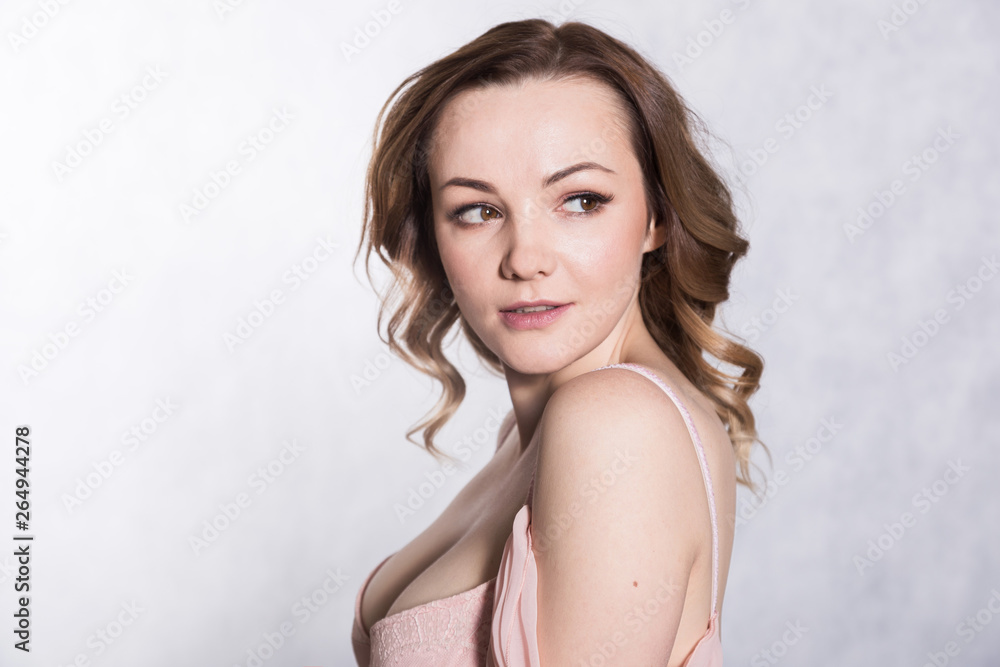 Portrait of beautiful young elegant female in pale pink wedding dress with big neckline, on a white background.